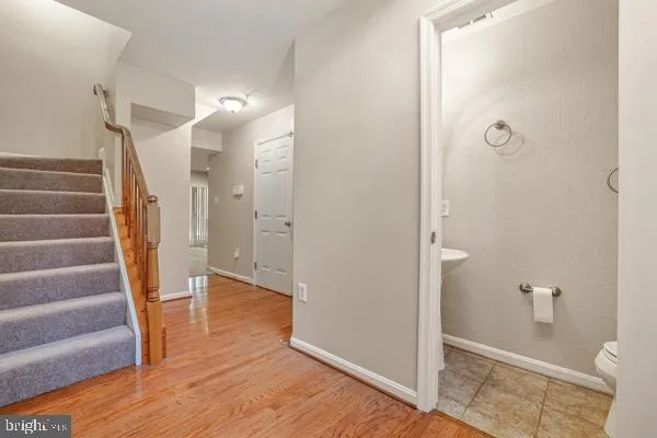 a view of an empty room with wooden floor and a bathroom