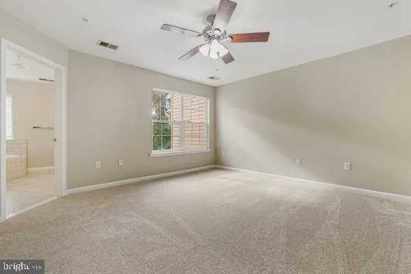 an empty room with windows and ceiling fan