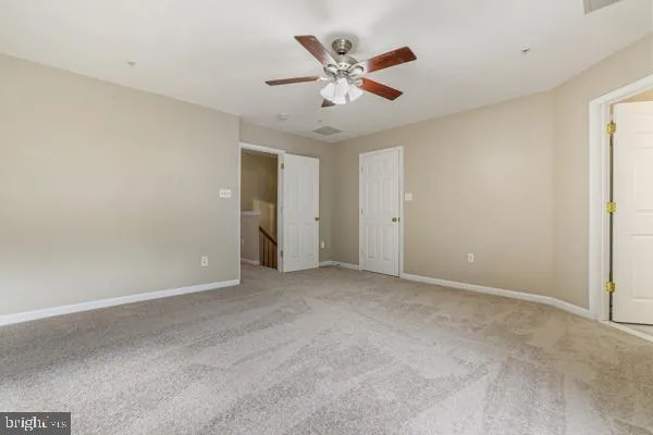 an empty room with ceiling fan and window