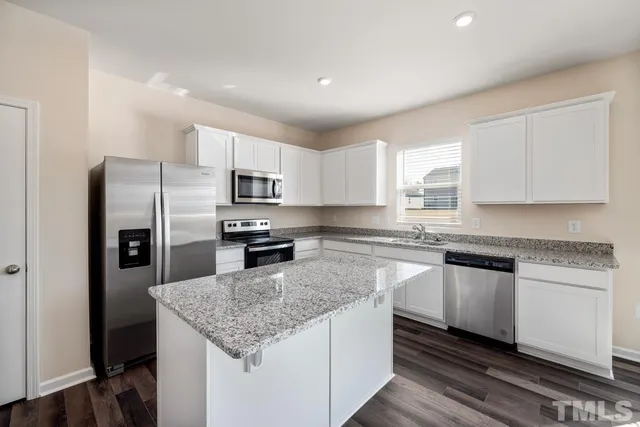 a kitchen with stainless steel appliances granite countertop a sink stove microwave and refrigerator