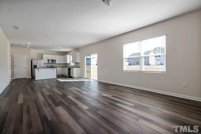 a view of empty room with wooden floor and window