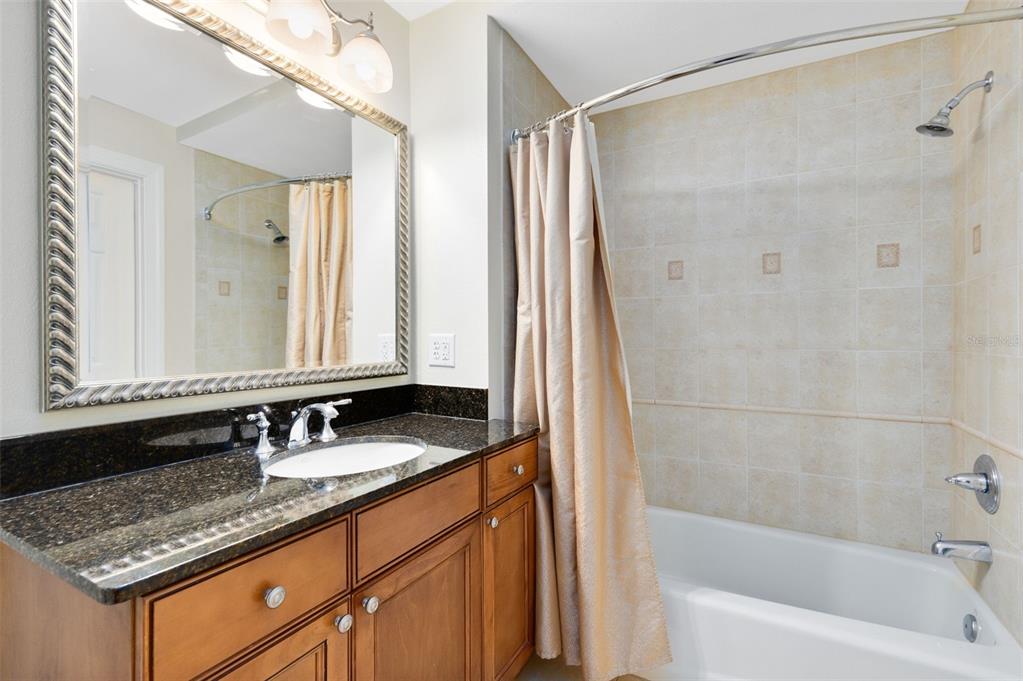 1360 Centre Ct Ridge Drive, Unit 201 Reunion, FL 34747 - Photo 23 of 29 a bathroom with a granite countertop sink a mirror a bathtub and shower