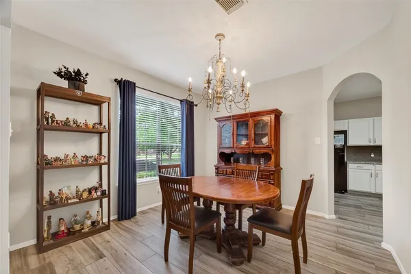 a kitchen with stainless steel appliances granite countertop a stove top oven a sink dishwasher a refrigerator and white cabinets with wooden floor