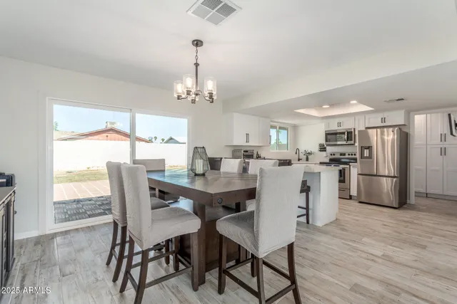 a view of a dining room and livingroom with furniture wooden floor a chandelier