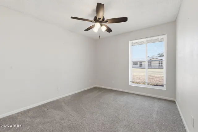 an empty room with a window and a ceiling fan