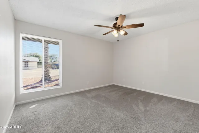 an empty room with windows and fan