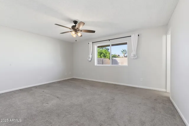 an empty room with windows and ceiling fan