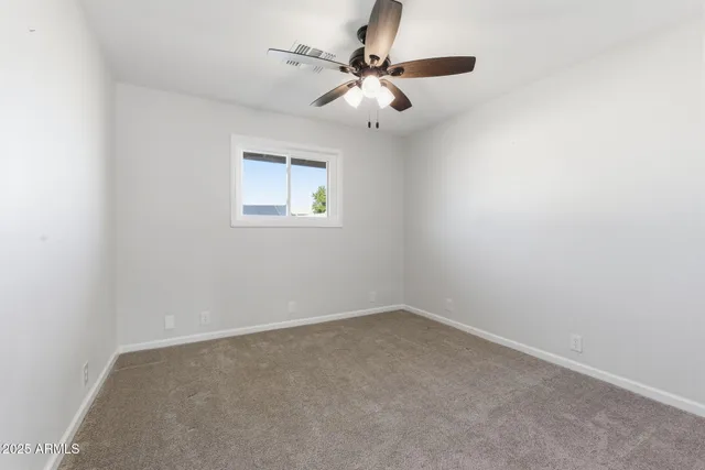 an empty room with a ceiling fan and a window