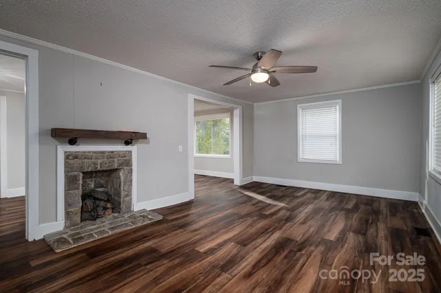 a view of an empty room with wooden floor fireplace and a window