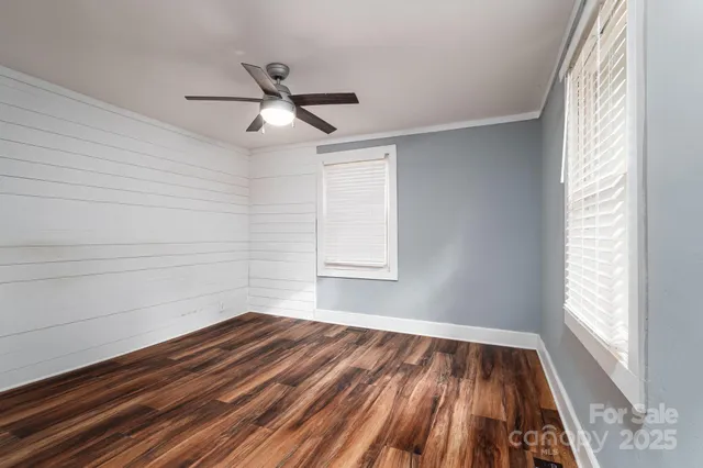 a view of empty room with wooden floor and fan