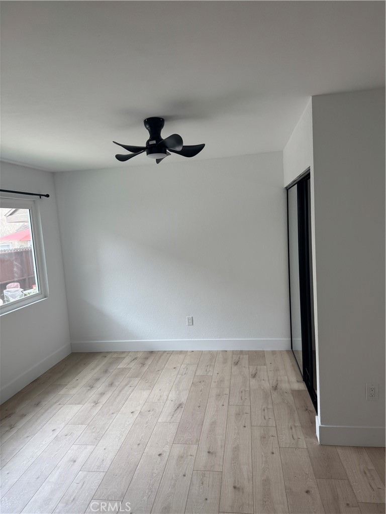 17422 Keelson Lane, Unit 3 Huntington Beach, CA 92647 - Photo 3 of 4 an empty room with wooden floor fan and windows