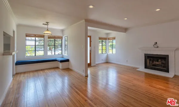 an empty room with wooden floor fireplace and windows