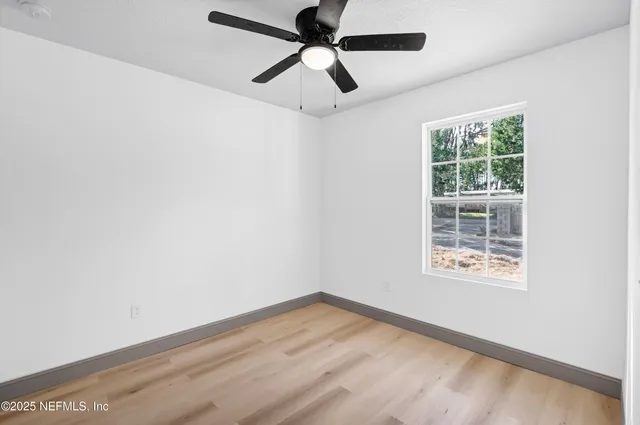 an empty room with a window and a ceiling fan