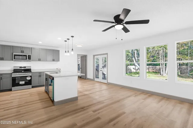 a view of kitchen with microwave a stove and white cabinets