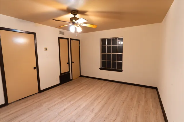 an empty room with a ceiling fan and wooden floor