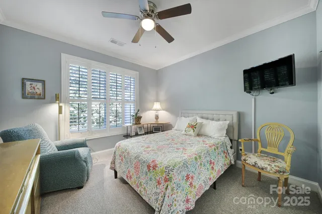 a bedroom with a bed couches and a flat tv screen