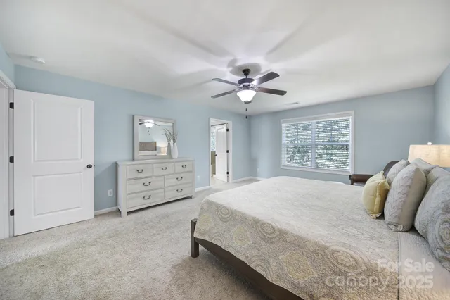 a bedroom with a bed couch chandelier and a ceiling fan
