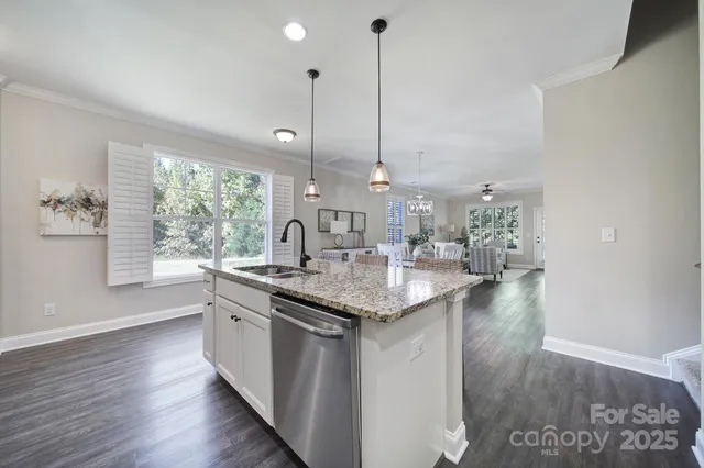 a kitchen with stainless steel appliances kitchen island granite countertop a table chairs refrigerator and sink