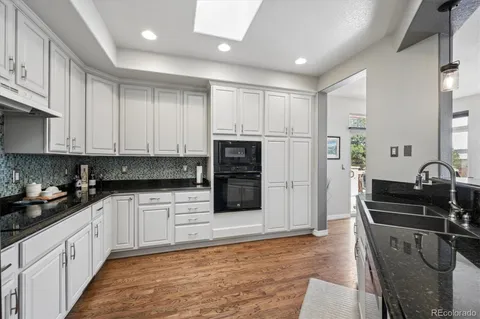 a kitchen with granite countertop a sink stove and cabinets