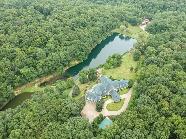 an aerial view of a house with a yard and greenery