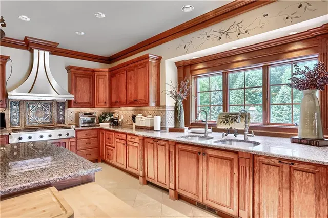 a kitchen with stainless steel appliances granite countertop a sink a stove a counter space and a window