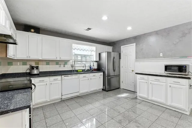a kitchen with granite countertop a sink appliances and cabinets