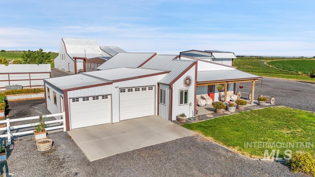 View of front of property with a metal roof, driveway, a porch, and a garage