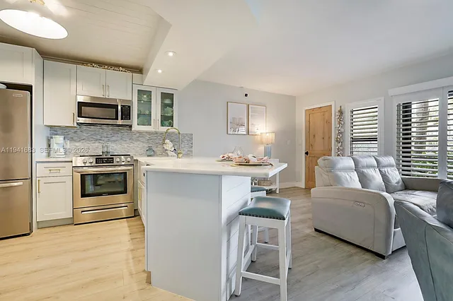 a kitchen with stainless steel appliances a stove a sink dishwasher a refrigerator and a microwave oven with wooden floor