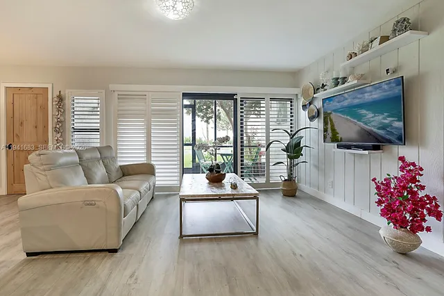 a living room with furniture flat screen tv and a large window