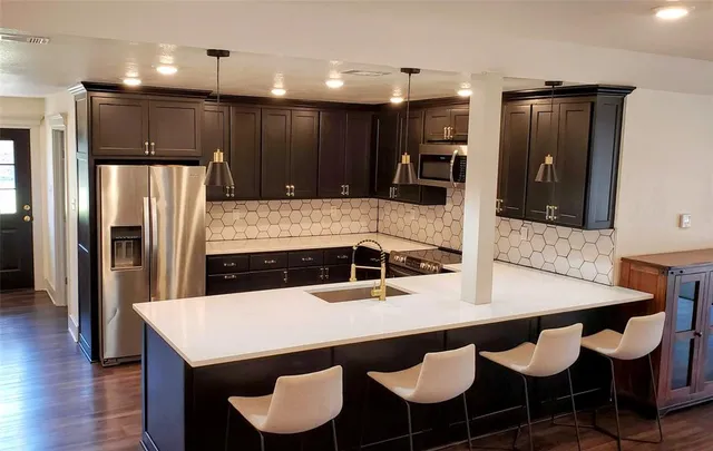 a kitchen with granite countertop a table chairs microwave and refrigerator