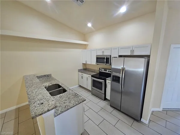 a kitchen with granite countertop a refrigerator sink and stove