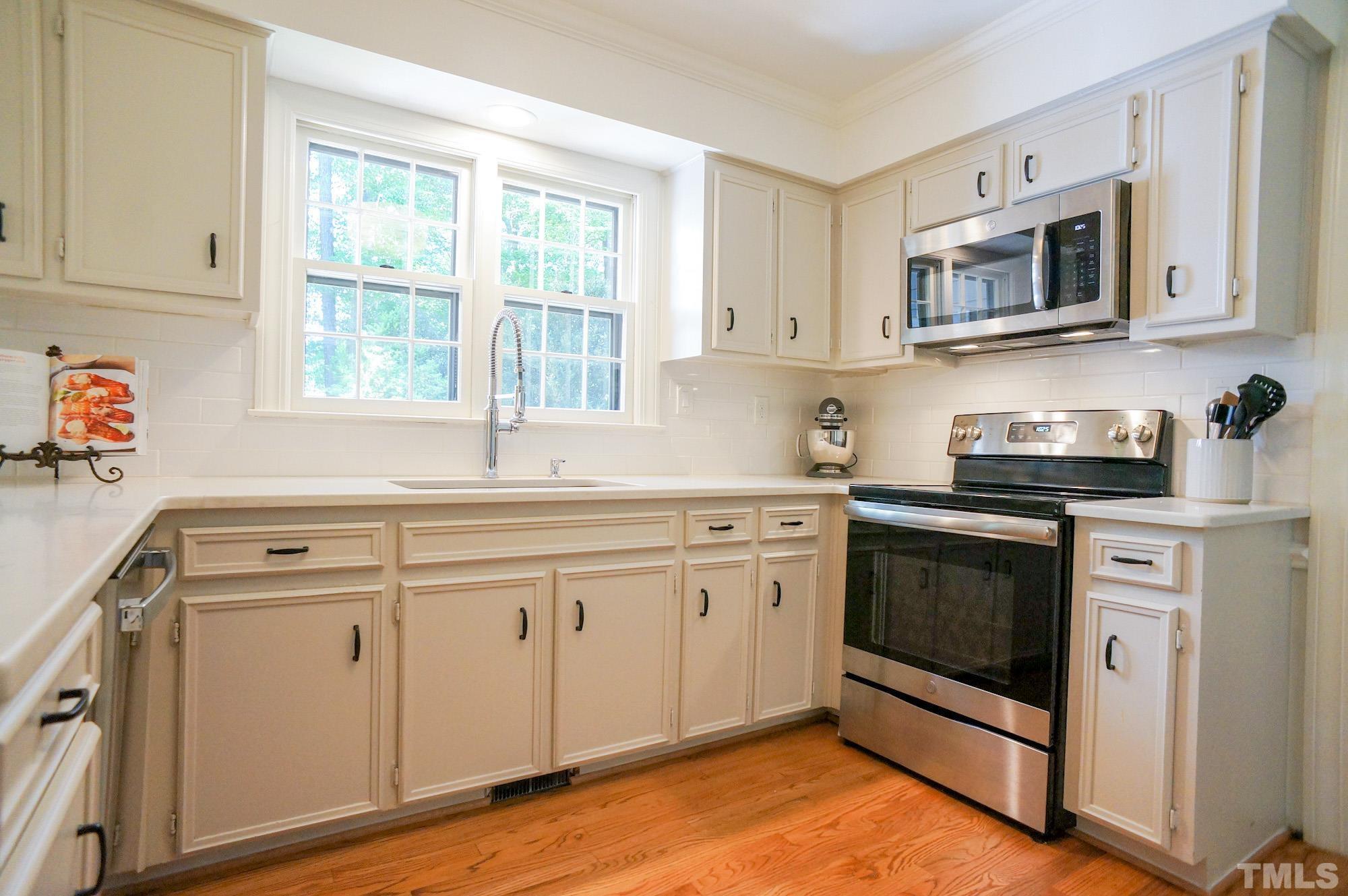 408 Emerywood Drive Raleigh, NC 27615 - Photo 14 of 44 a kitchen with granite countertop white cabinets stainless steel appliances and a window