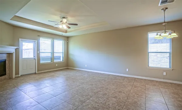 a view of an empty room with window and chandelier fan