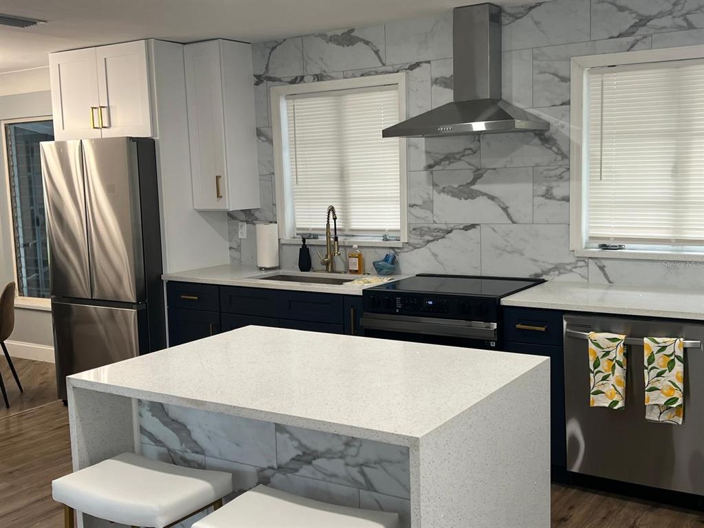 905 West 11th Avenue Mount Dora, FL 32757 - Photo 5 of 25 a kitchen with stainless steel appliances a white refrigerator a sink a stove and white cabinets