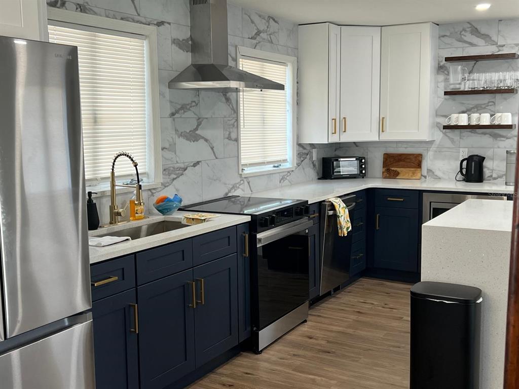 905 West 11th Avenue Mount Dora, FL 32757 - Photo 7 of 25 a kitchen with stainless steel appliances granite countertop a sink stove and refrigerator