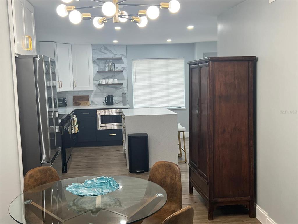 905 West 11th Avenue Mount Dora, FL 32757 - Photo 9 of 25 a kitchen with stainless steel appliances granite countertop a refrigerator a stove a sink dishwasher and a dining table with wooden floor