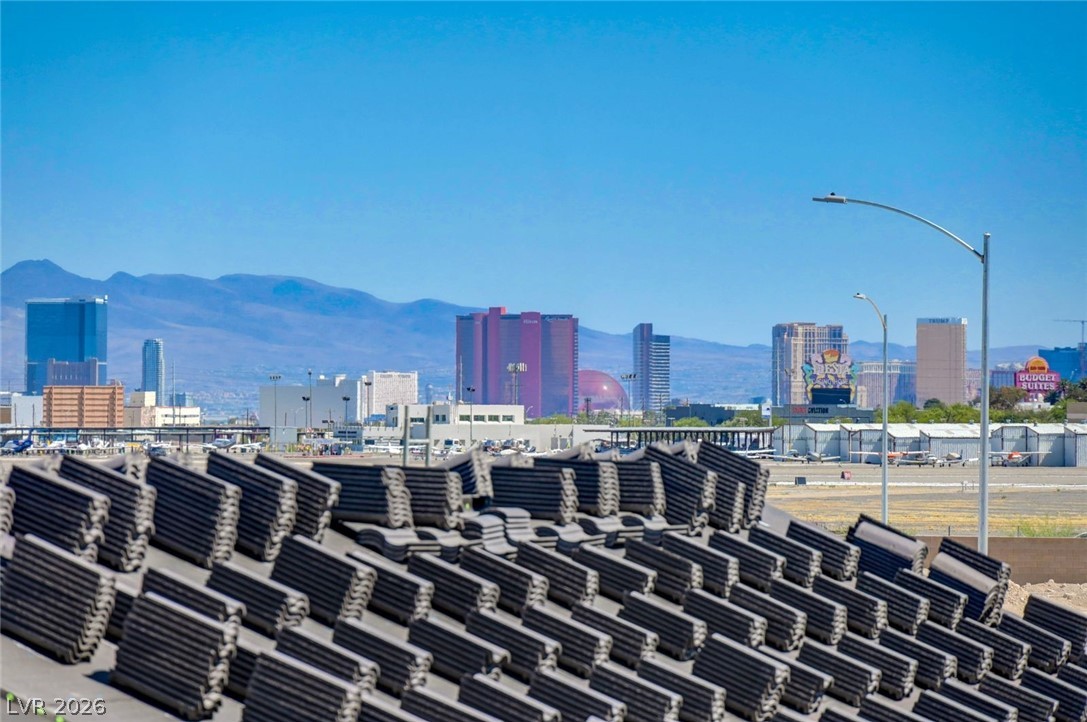 3318 North Decatur Boulevard, Unit 2072 Las Vegas, NV 89130 - Photo 34 of 50 Distant city buildings frame a desert landscape under a clear blue sky, with roof tiles in the foreground.