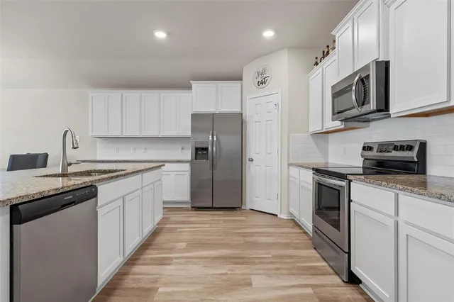 a kitchen with stainless steel appliances granite countertop a refrigerator a stove top oven a sink and dishwasher