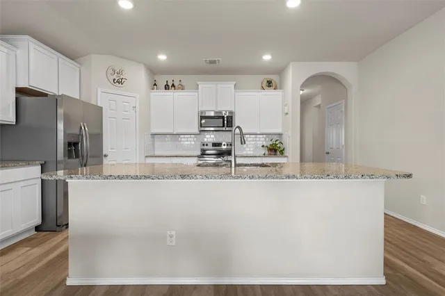 a large kitchen with kitchen island a large counter top space a sink stainless steel appliances and cabinets