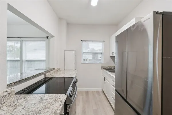 a kitchen with granite countertop a refrigerator and a sink