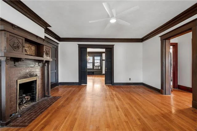 a view of an empty room with wooden floor fireplace and a window