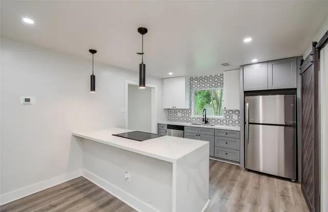 a kitchen with kitchen island a sink appliances and wooden floor