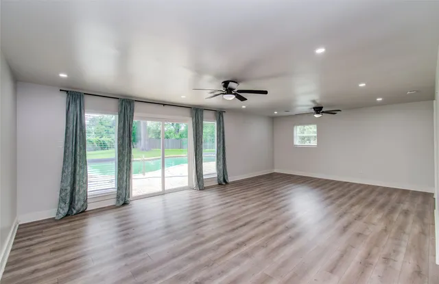 a view of an empty room with a window and wooden floor