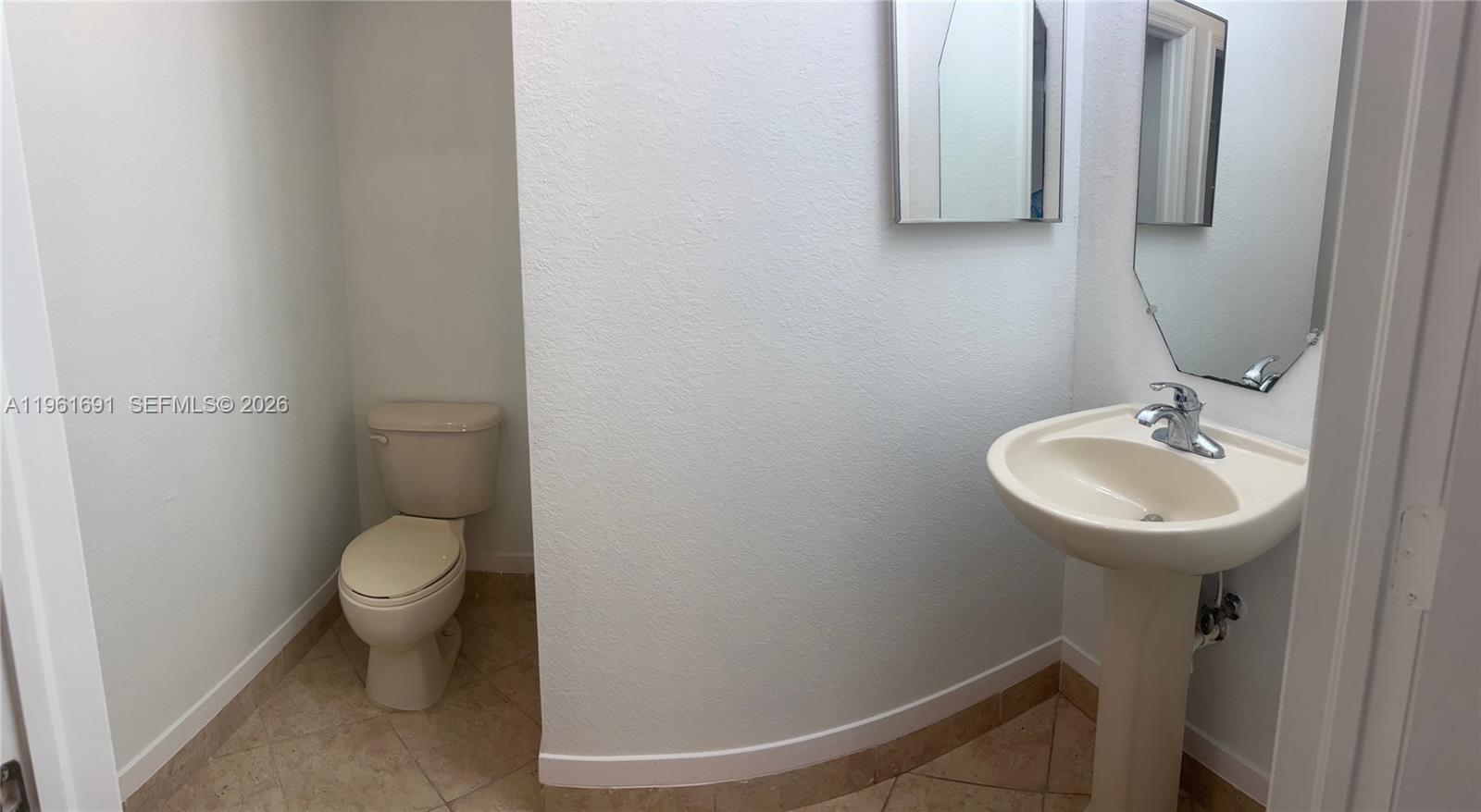 12458 Southwest 125th Terrace, Unit 12458 Miami, FL 33186 - Photo 4 of 22 a bathroom with a toilet sink and mirror