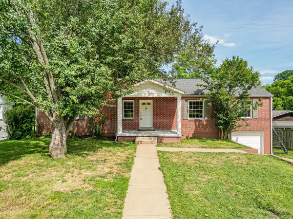 a front view of a house with a yard and trees