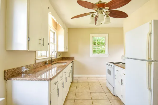 a kitchen with granite countertop cabinets a sink stainless steel appliances and a window