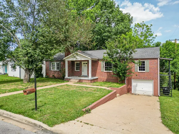 a front view of a house with a yard and trees