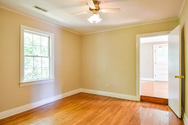 a view of an empty room with wooden floor and a window