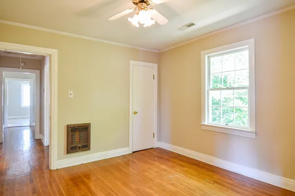 a view of an empty room with wooden floor and a window