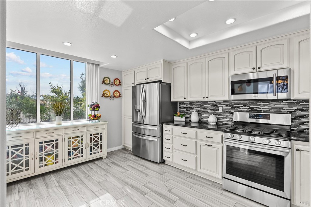 25726 Emerson Lane Stevenson Ranch, CA 91381 - Photo 12 of 45 a kitchen with stainless steel appliances a stove a refrigerator a sink cabinets and wooden floor
